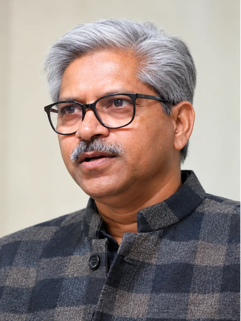 R. K. Sharma speaking, in a checked jacket